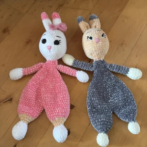 Handgjorda kanin-gosedjur i mjuk plysch - Två söta handgjorda kanin-gosedjur i mjuk plysch. En är rosa med vita och beige detaljer samt en rosett på ena örat, den andra är grå med vita och beige detaljer. Båda har broderade ansikten och långa öron. Perfekt som present eller mysig kompis.