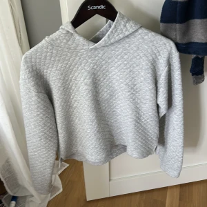 Ljusgrå hoodie från Kappahl - Säljer en ljusgrå hoodie från Kappahl med quiltad struktur. Tröjan har lång ärm och en mysig huva. Perfekt för en avslappnad stil och passar bra till jeans eller leggings. Storlek 158/164