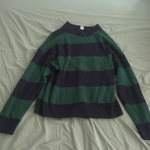 Randig tröja från H&M Divided - Säljer en randig tröja från H&M Divided i grönt och mörkblått. Tröjan har långa ärmar och en bekväm passform. Perfekt för en avslappnad stil.