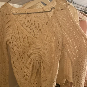 Tunn Beige stickad tröja - Säljer en tunn beige stickad tröja från Only med v-ringning och snygg snörning framtill. Tröjan har ett fint mönster och långa ärmar. Passar bra till både jeans och kjol. 🌟