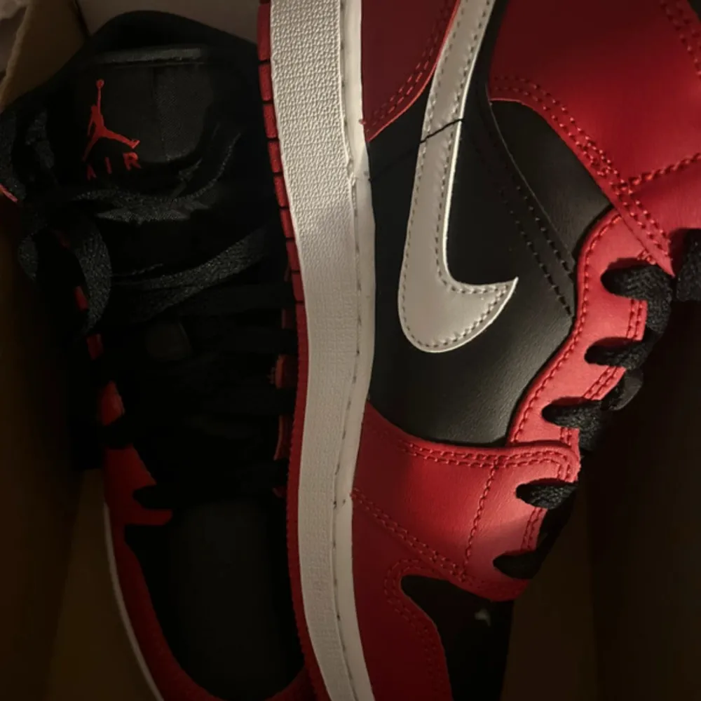 Säljer ett par klassiska Nike Air Jordans med svart bas, röda paneler och vita detaljer. Skorna har vit swoosh, svart snörning och röd Air Jordan-logga. Perfekta för dig som gillar streetstyle och sneakers med ikonisk design.. Kengät.