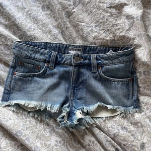 NYA Weekday lågmidjade shorts med fransar  - Säljer ett par blå jeansshorts från Weekday som endast blivit testade med lapp kvar som är slutsålda. Jeansen heter ”VENUS FRAYED LOW WAIST DENIM HOTPANTS” supersnygga till sommaren!  39cm rakt över🫶