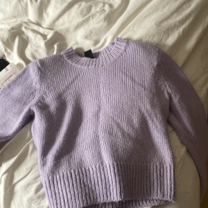 Ljuslila stickad tröja från Lindex - Superfin ljuslila stickad tröja från Lindex. Tröjan har rund halsringning, långa ärmar och bred ribbstickning vid ärmslut och nederkant. Puffar vid axlarna.