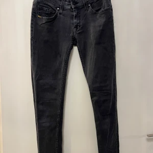 Svarta skinny jeans- Tiger Of Sweden  - Säljer ett par svarta skinny jeans med klassisk femficksdesign och snygga sömdetaljer längs sidorna. 