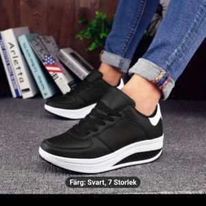 Svarta sneakers med vit sula - Snygga svarta sneakers med vit, tjock sula och svarta snören. Skorna har en sportig look och passar perfekt till jeans eller träningskläder. Ovandelen är i syntetmaterial och sulan har bra grepp. Perfekta för dig som vill ha bekväma och stilrena skor.