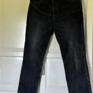 Svarta jeansbyxor från ASOS - Svarta jeansbyxor från ASOS med klassisk femficksdesign och raka ben. Jeansen har lite pösigare passform och stängs med dragkedja och knapp. Perfekta för en stilren och avslappnad look. Strl 34/30. Hör av er vid intresse/frågor!