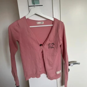 Rosa kofta från Odd Molly - En söt rosa kofta från Odd Molly med broderad text på bröstet. Koftan har v-ringning, långa ärmar och knäppning framtill. Storlek 0 som motsvarar xs/xxs
