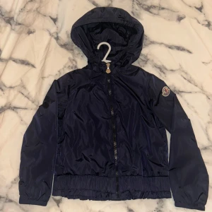 Moncler jacka - Säljer en mörkblå vindjacka från Moncler med huva och dragkedja framtill. Moncler jacka för barn storlek:130cm