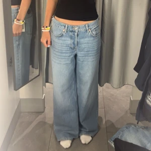 Baggy jeans - Säljer ett par ljusblå jeans med wide leg passform. Byxorna har klassisk femficksdesign, knappgylf och är lågmidjade. Perfekta för en avslappnad och trendig stil.