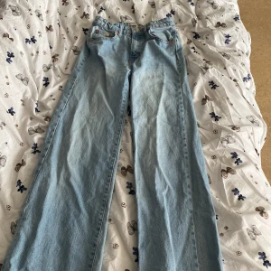 Ljusblå wide leg jeans från 157 - Säljer ett par ljusblå jeans från 157 med wide leg-passform och klassisk femficksdesign. Jeansen har hög midja och raka, vida ben. Perfekta för en avslappnad och trendig stil. Stängs med knapp och dragkedja.