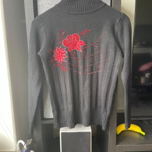 Svart polotröja med röda blommor - Lite nooorig vid armhålan