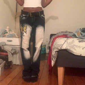 Unika jeans - Säljer dessa unika jeans i baggy modell med coolt bleachat mönster och broderad fjäril på vänster sida. Jeansen har en avslappnad passform, låg midja och raka ben som ger en snygg streetwear-look. De är i ett mjukt, slitstarkt denimtyg som både sitter skönt och håller stilen hela dagen🩷 Storlek M, jag är 159 cm för referens 