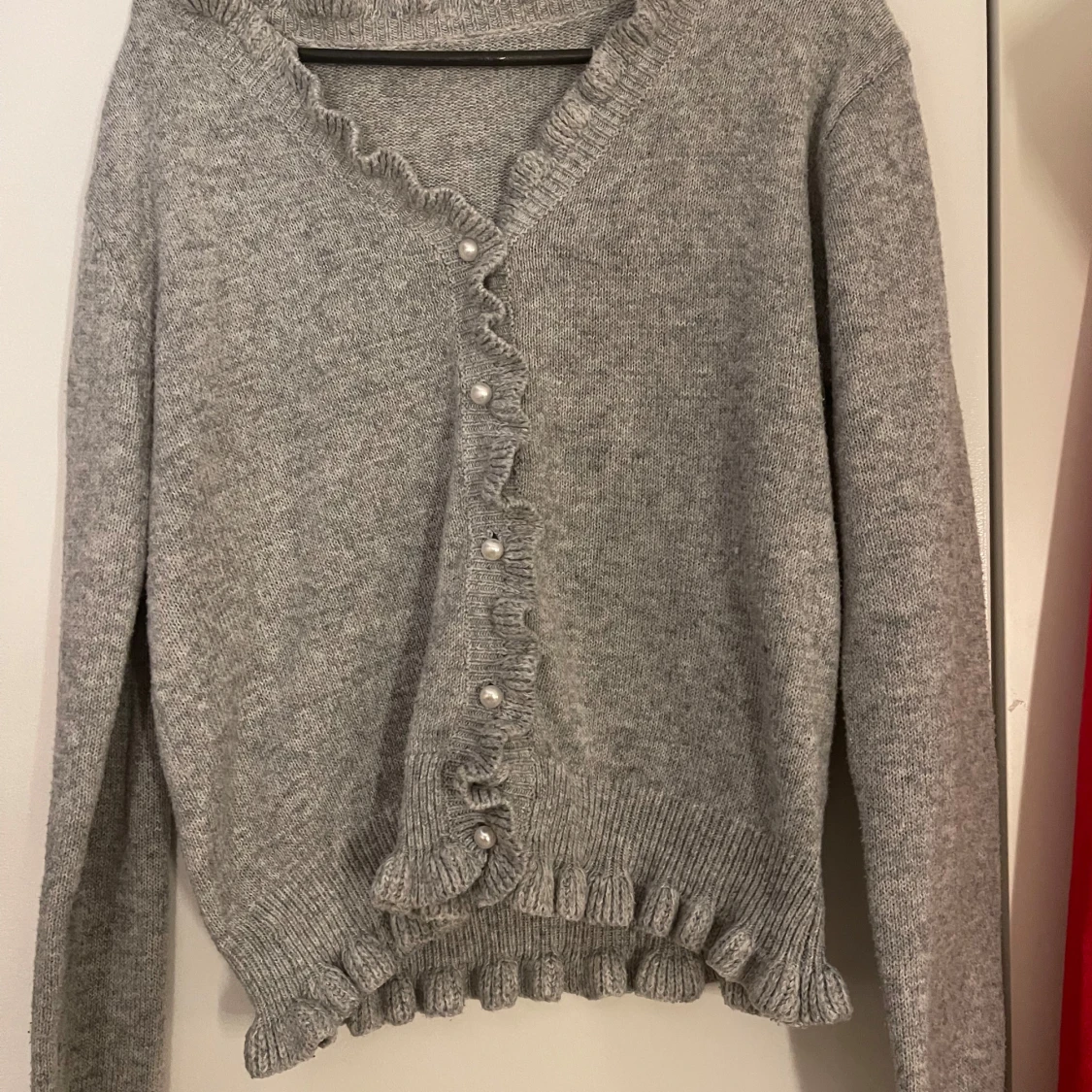 Grå stickad kofta med volang och pärlknappar