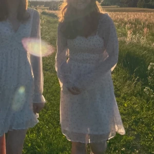 Vit blommig klänning med långa ärmar - Superfin vit klänning med små rosa blommor och långa ärmar. Perfekt för sommar eller midsommar! Endast använd 1 gång