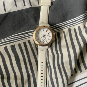 Vit klocka från GANT med gulddetaljer - Snygg klocka från GANT med vit urtavla, vit silikonrem och guldfärgad ring runt urtavlan. Klockan har tydliga index och datumvisning. Perfekt accessoar för dig som gillar stilrena detaljer.