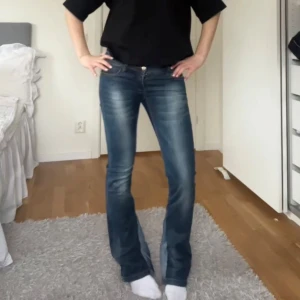 Lågmidjade utsvängda jeans - Mörkblå lågmidjade utsvängda jeans som är utsydda. I bra skick förutom en knapp som saknas (se sista bild). Midjemått finns bland bildern och hela längden av jeansen är 99 cm💕