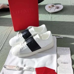 Valentino sneakers  - Säljer ett par vita Valentino Open sneakers med ett brett svart band över mitten. Perfekta för dig som gillar stilrena och exklusiva sneakers.❤️De är aldrig använda så som helt nya❤️Köpte dom för 5900kr 