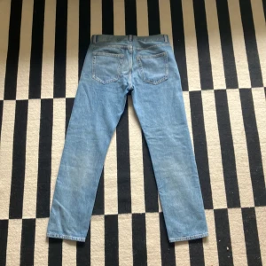 Blå jeans Park Regular Fit från Arket - Säljer ett par klassiska blå jeans från Arket, modell Park Regular Fit. Jeansen har normal passform, raka ben och fem fickor. Stängs med knappar. Perfekta till vardags och enkla att matcha. 
