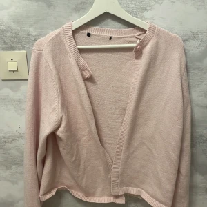 Ljusrosa kofta med knappar - Säljer en söt ljusrosa kofta, Den har en mjuk och bekväm känsla, perfekt för lager-på-lager outfits. Koftan har långa ärmar och ribbade kanter som ger en stilren look. 