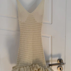 Beige stickad strandklänning med volangdetalj - Snygg beige stickad klänning med volangdetalj vid fållen. Fin till stranden eller varmare väder.❣️köpt utomlands, aldrig använd med prislappen kvar. 