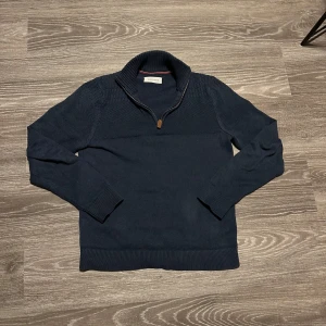 Mörkblå stickad tröja från Pier One - Snygg mörkblå stickad tröja från Pier One med dragkedja vid halsen i storlek S. Perfekt för kyligare dagar med sin stilrena design och långa ärmar. Passar bra till både jeans och chinos.