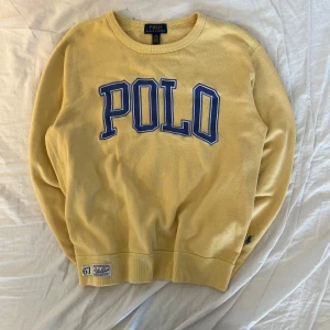 Gul tröja från Polo Ralph Lauren - Säljer en gul tröja från Polo Ralph Lauren med blå text på framsidan. Tröjan har en rund halsringning och är tillverkad i bomull. Perfekt för en avslappnad stil. Säljer då jag har växt ur den, medela vid minsta funderingar! 👍