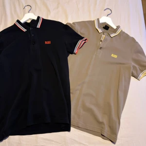 Pikétröjor från Boss - Säljer två stilrena pikétröjor från Boss i storlek M. En svart med röda och vita detaljer samt en beige med gula och vita detaljer. Båda har klassisk krage och knappar framtill. Perfekta för en avslappnad men snygg look.