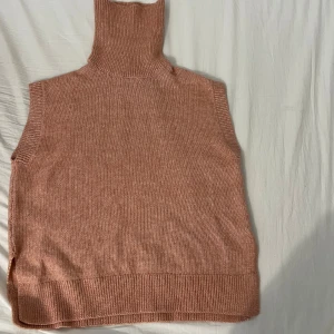 Rosa stickad väst från Lindex - Säljer en mysig rosa stickad väst från Lindex. Västen har en hög krage och ribbade kanter som ger en stilren look. Perfekt för lager-på-lager under kyligare dagar.