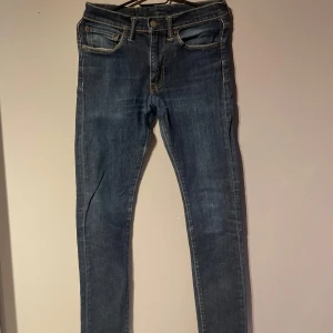 Blå jeansbyxor från Levis - Snygga blå jeansbyxor från Levis. De är slim fit och är storlek 29/32. Märkeslappen syns tydligt på baksidan. De har haft ett hål vid skrevet men är lagat och syns knappt tycker jag.