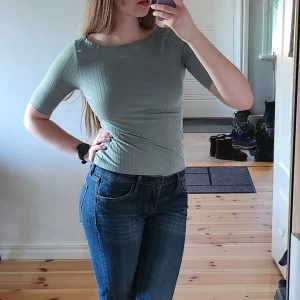 Grön ribbad topp - Snygg grön ribbad topp med korta ärmar. Perfekt för en stilren och bekväm look. Passar bra till jeans eller kjol för en avslappnad stil.