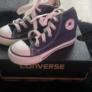 Blå Converse All Star sneakers - Säljer ett par klassiska blå Converse All Star sneakers med vita snören och gummisula. Skorna har den ikoniska logotypen på sidan och är perfekta för en avslappnad stil.