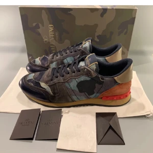 Valentino Rockrunner - Säljer ett par Valentino Rockrunner sneakers i ett coolt camouflage-mönster. Skorna har en mix av färger som blå, grön och röd med snygga detaljer i skinn och mocka. Perfekta för att ge din outfit en unik touch. Tar emot byten. Hör av dig vid eventuella byten av andra skor helst storlek 45. 44 men passar 45. OBS!!! Dustbag ingår ej 