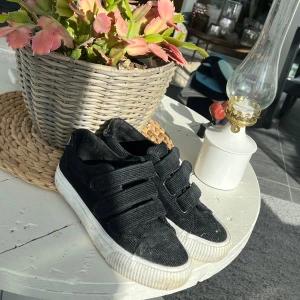Svarta sneakers med kardborreband - Snygga svarta sneakers från EVEN&ODD i storlek 38. Sula/underdelen på skon är oren men inte tyget/innuti. Har inte haft tid att använda dessa så där av att jag säljer. Skulle behövas rolla av för att få bort dam bara så är ovansidan som ny💕