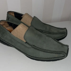 Gröna loafers från Gabor - Snygga gröna loafers från Gabor i skinn. De har en stilren design med diskreta sömmar och en bekväm passform. Perfekta för en avslappnad men ändå elegant look.