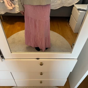 Rosa långkjol med blommigt mönster - Säljer en söt rosa långkjol med små blommor. En liten lagning men syns inte när man har på sig kjolen