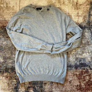 Grå tröja från Massimo Dutti - Säljer en stilren grå tröja från Massimo Dutti. Tröjan är tillverkad i en mjuk bomullsblandning och har långa ärmar samt ribbade muddar vid ärmslut och nederkant. Perfekt för en avslappnad och elegant look.