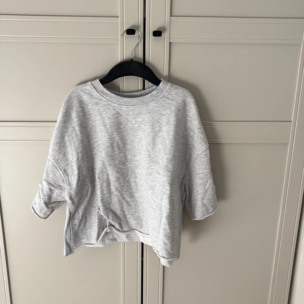Säljer en stilren grå tröja från Zara med trekvartsärm och rund hals. Perfekt för våren. Tröjan har en lös passform och är tillverkad i ett mjukt material.. Neuletakit & Villapaidat.