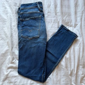 Blå jeans från Replay - Snygga blå jeans från Replay med klassisk femficksdesign och broderade bakfickor. Modellen är Anbass och är i storlek 31. Passformen är slim och de är tillverkade i ett bekvämt denimtyg.