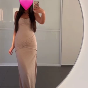 Begie långklänning - Säljer min fina beige axelbandslösa långklänning med draperade detaljer i midjan och vid bröstet. Är stretchig och såå bekväm. Älskar!! Endast använd under några timmar.