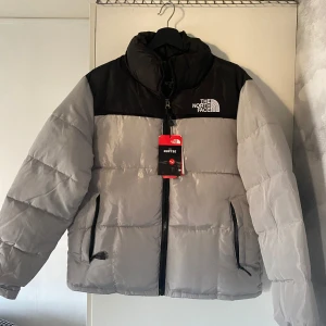 The north face puffer jacka - Säljer denna supersnygga och oanvända the north face puffer jacka som är med tags och allt. Den är helt ny och köpt förra månaden, februari. Säljer den p.g.a tycker det är inte värt att ha på mig den nu. Det är varmt inuti den och den är jätte varm och bekväm. Det står att den är i storlek l men den passar mer som m tycker jag. Skickar såklart inom 24h. Kan gå ner i priset vid en snabb köp, priset är inte hugget i sten!