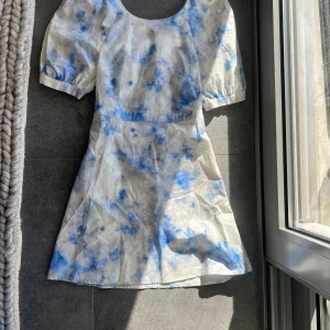 Blå- och vitmönstrad klänning från Baum und Pferdgarten - Superfin sommarklänning från Baum und Pferdgarten i storlek Small. Blå och vit mönstrad bomull med vacker knytdetalj i ryggen och puffärmar. Öppen rygg. Anvönd några få gånger men i fint skick!