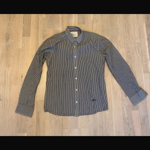 Randig skjorta från Selected Homme - Snygg randig skjorta från Selected Homme i svart och vitt. Skjortan har långa ärmar och knappar framtill. Perfekt för en stilren look.