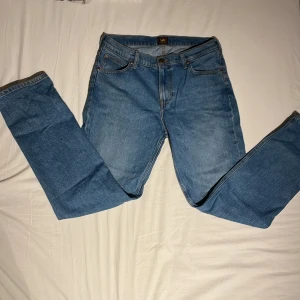 Blå jeans från Lee - Säljer ett par klassiska blå jeans från Lee. De har en normal passform med raka ben och fem fickor. Perfekta för en avslappnad stil. Tillverkade i slitstarkt denim. Skick 9/10 andvänt ca 3 gånger. Nypris:- 1099 mitt pris 250