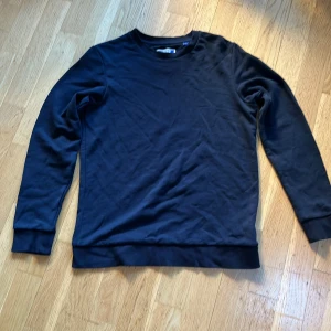 Marinblå tröja från Jack & Jones - Säljer en stilren svart tröja från Jack & Jones. Tröjan har långa ärmar och en rund halsringning. Perfekt för en enkel och klassisk look. Passar bra till både jeans och chinos.