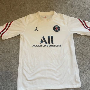 PSG tröja  - Säljer en vit PSG shirt  från Jordan. Perfekt för sommaren. Tröjan har några fläckar på sig men som borde gå bort om man tvättar den ordentligt. Pris är som vanligt förhandlingsbart. Vid frågor och funderingar kontakta gärna mig
