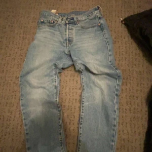 Levi's 501 jeans - Klassiska blå Levi's 501 jeans med knappgylf och femficksdesign. Perfekta för en avslappnad stil. Tillverkade i slitstarkt denim. W26 L28