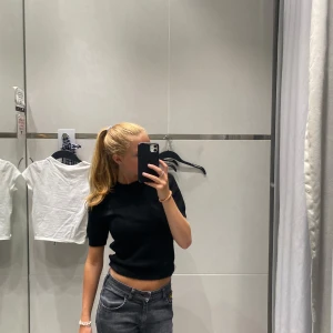 Svart croppad tröja - Säljer en stilren svart croppad tröja med korta ärmar. Perfekt för en trendig look. Passar bra till jeans eller kjol.