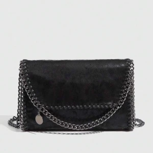 Svart axelväska med kedjedetaljer - Snygg svart axelväska med kedjedetaljer och en stilren design. Väskan har en praktisk dragkedja och en kedja som axelrem. Perfekt för att ge en edgy touch till din outfit.