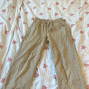 Beige linnebyxor  - Säljer ett par bekväma beige linnebyxor från 157. Byxorna har en elastisk resårmidja med snörning för justerbar passform. Storlek 130