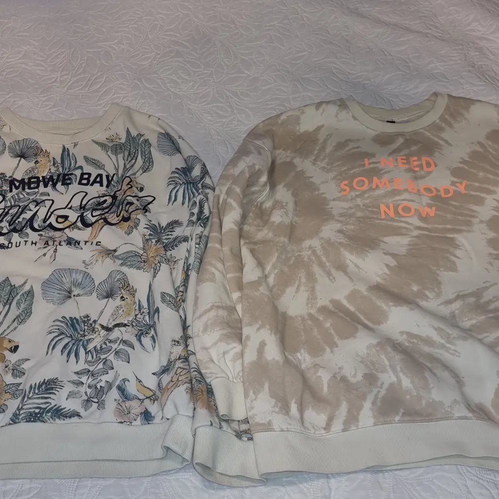 Säljer två snygga tröjor. Den ena har ett tropiskt blommönster med texten 'Mows Bay' och den andra är beige med batikmönster och texten 'I Need Somebody Now'. Perfekta för en avslappnad stil! Mkt fint skick. Neuletakit & Villapaidat.